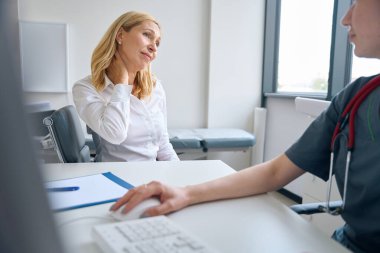 Hüzünlü hasta, muayene sırasında doktorun önünde boynunun kenarına elleriyle dokundu.