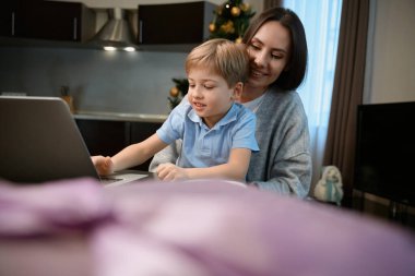 Küçük çocuklu mutlu bir kadın internetten alışveriş yapıyor. Yılbaşı hediyesi alıyor.
