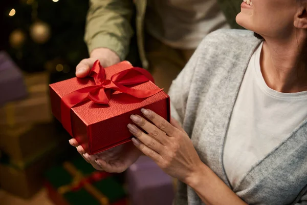 Unrecognizable man giving present box to unknown woman while celebrating Christmas holiday together
