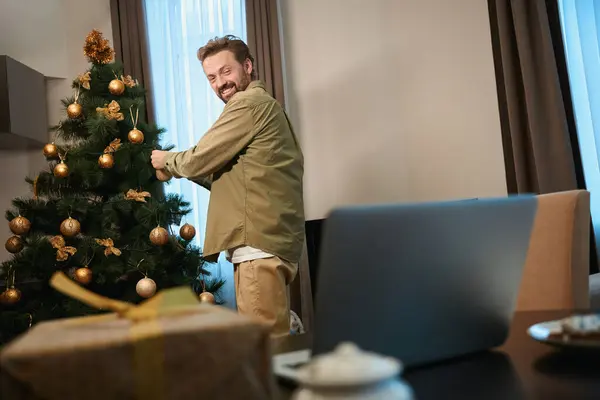 Fröhlicher Mann Schmückt Weihnachtsbaum Und Unterhält Sich Online Laptop Auf — Stockfoto