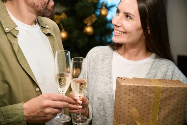 Smiling woman celebrating Christmas with man holding glasses with champagne enjoying New Years Eve