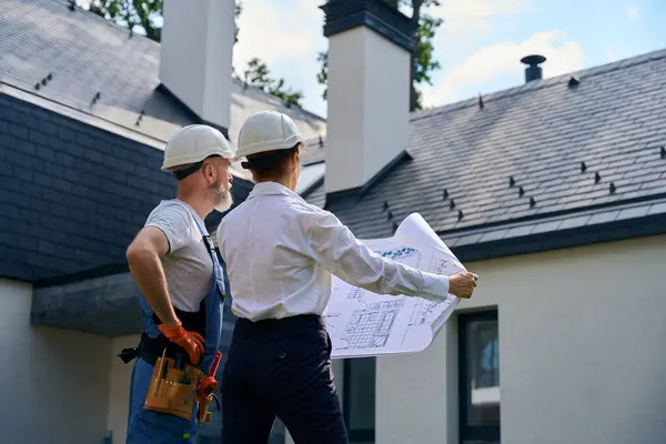 Byggnadsarbetare Och Byggnadsinspektör Med Arkitektritningar Framför Nybyggda Hus — Stockfoto