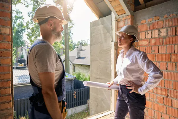 未完成の住宅の内部の請負業者に話す建築図面を用いる建築検査官 — ストック写真