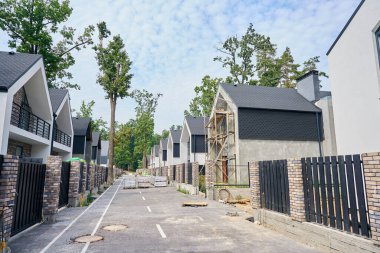 Asfaltlı yol boyunca kereste paletlerinde inşaat malzemeleri bulunan tamamlanmamış özel konut satırları