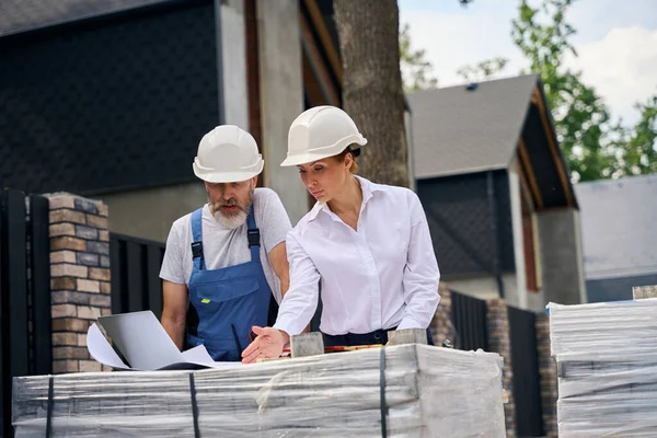 Allvarlig Kvinnlig Byggingenjör Pekar Något Ritningar Till Byggmästare Byggtomt — Stockfoto
