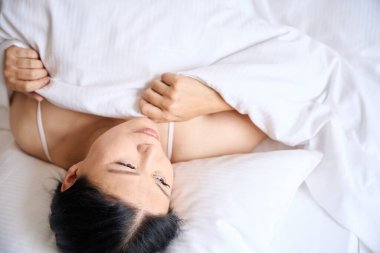 Sakin kadın, yumuşak beyaz yastığın üzerinde uzanırken kendini yoruyor.