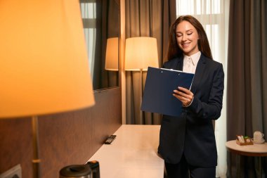 Memnuniyet verici ev idarecisi sabah misafir odasında beklerken panoya yazı yazıyor.