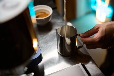 Barista kafede bir fincan kahve hazırlamak için kapuçino yapıyor.