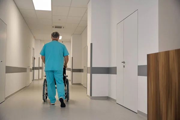 Back View Healthcare Worker Pushing Wheeled Chair Handles Empty Hospital — Stock Photo, Image