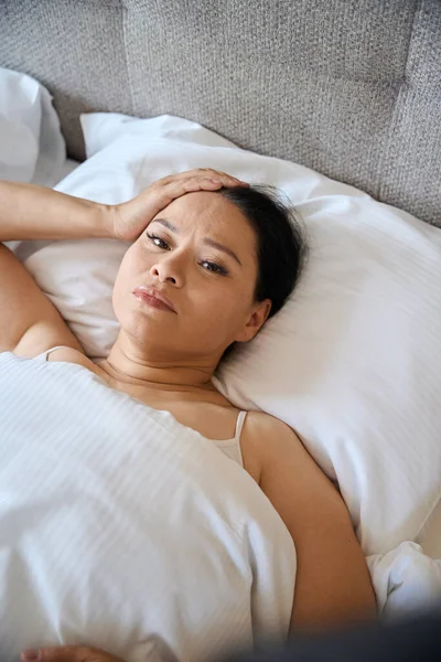 悲哀的女人躺在床上裹着毛毯 用手触摸着头 — 图库照片