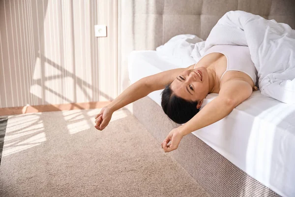 Fröhliche Frau Mit Bettdecke Bedeckt Liegt Auf Dem Rücken Bett — Stockfoto