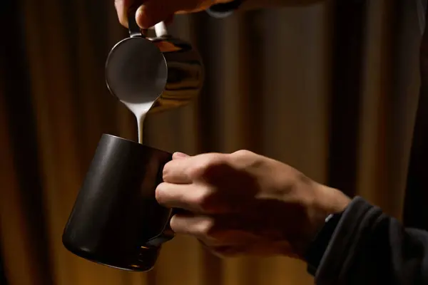 Coffee maker hands pouring milk from pitcher preparing coffee in cafe