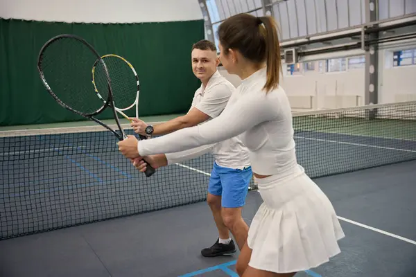 田径女子与男子指导员打网球提高技术学习打进室内场地 — 图库照片