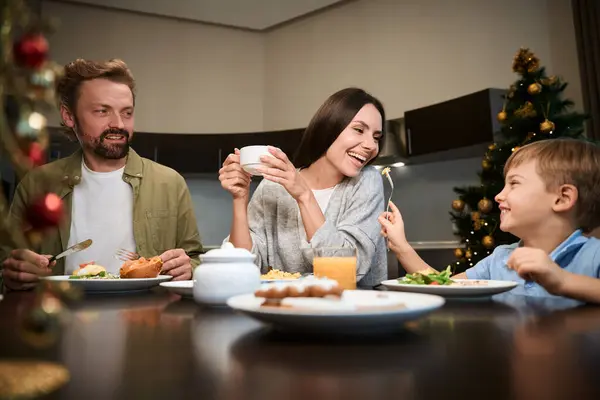 Charming family enjoying lazy morning in hotel having festive breakfast together celebrating Christmas