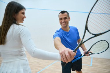 Sporcu koçu, iç sahada becerilerini geliştirmek için kadın egzersizleriyle squash antrenmanı yapıyor.