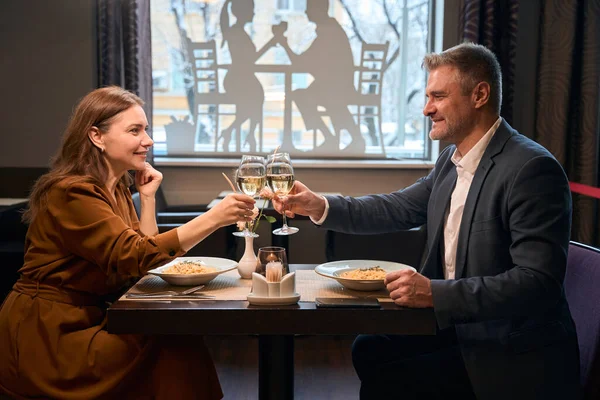 現代のホテルのレストランでメガネからワインを試飲する幸せな大人の白人カップルの側面の景色 ロマンチックな日付とイベントのコンセプト — ストック写真