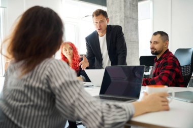 Öfkeli patron, diğer iş arkadaşlarıyla birlikte dizüstü bilgisayarda çalışan kadın çalışana görevi açıklıyor. İş sorunları, yanlış anlaşılmalar.