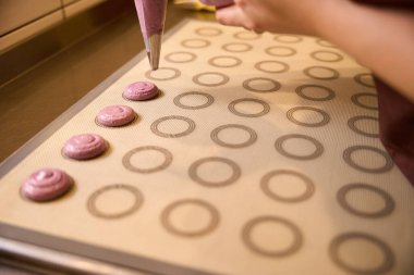 Makarna hamurunu hamur torbasından fırın paspasına sıkıştırırken çekilmiş bir fotoğraf.