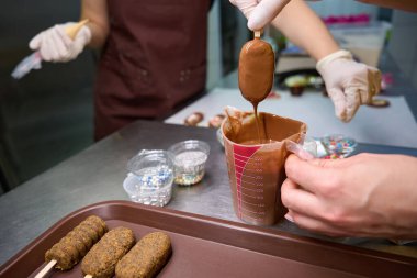 Pasta şefinin, meslektaşının da yardımıyla çikolatalı dondurmaya bandırdığı kesilmiş bir fotoğraf.