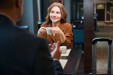 Gülümseyen kadın kafede oturuyor ve bir adamla kahve içiyor.