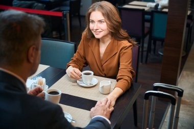 Kahve içerken ve el ele tutuşurken bir otel restoranında oturan çift.
