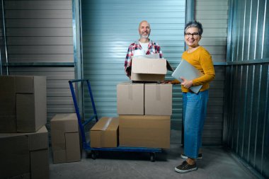 Karton kutuların yanında bir adam ve bir kadın.