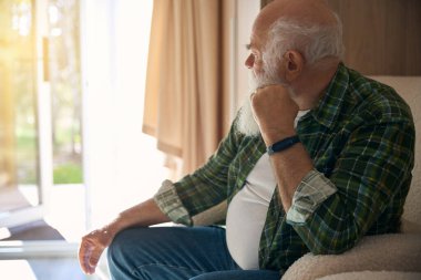 Sıcak ekose gömlekli yaşlı adam rahat bir sandalyede dinleniyor, dinlenme alanına yerleşti.