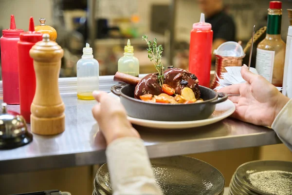 Restaurant staff serves meat in a serving pan, traditional serving is used