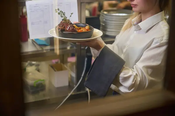 Waitress serves meat, decorated with sprigs of thyme, the woman has a neat manicure