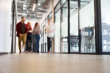 Bulanık manzaralı insanlar büyük panoramik pencereleri olan parlak ofis koridorlarında yürüyorlar, erkek ve kadınlar öğle arasından sonra işyerlerine dönüyorlar.