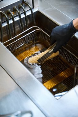 Kiev pirzolası kızartır, koruyucu eldiven giyer.