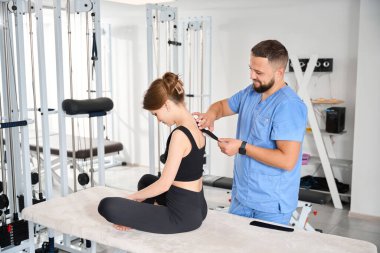 Kadın hastalara siyah bant uygulayan fizyoterapist, rahat siyah elbiseli kadın.