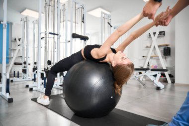 Güzel bir kadın eğitmenin gözetiminde spor yaparak kas germe egzersizleri yapıyor.