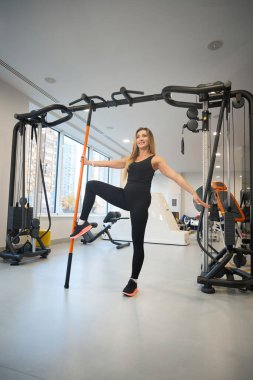 Antrenman kıyafetli güzel bir kadın fiziksel egzersizleri dengede yapar, özel spor sopaları kullanır.