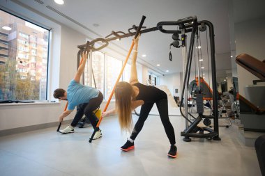 Kadınlar ve erkekler esneme egzersizleri yaparlar, özel spor sopaları kullanırlar.