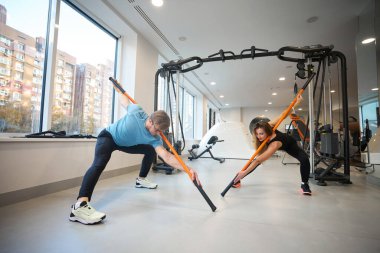 Kadınlar ve erkekler esneme egzersizleri yaparlar, özel spor sopaları kullanırlar.