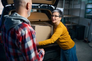 Sarı kazaklı kadın arabasının bagajından bir kutu çıkardı..