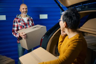 Kel adam kısa saçlı bir kadınla konuşurken karton bir kutu çıkardı.