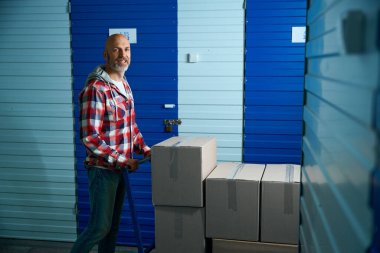 Hareket eden bir oyuncak bebek kullanarak karton kutularda bir şeyler taşıyan bir adam.