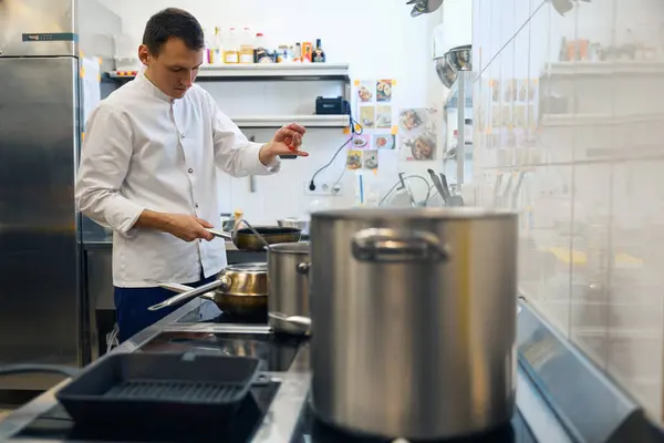 Kerel Uniform Bereidt Eten Een Restaurant Keuken Hij Gebruikt Specerijen — Stockfoto