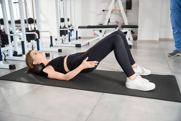 Kadın paspasın üzerinde egzersiz yapıyor, kadın bantlarla kaplı.