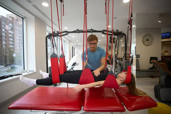 Employee of a wellness center fixes a patient in a suspension loop system using modern equipment