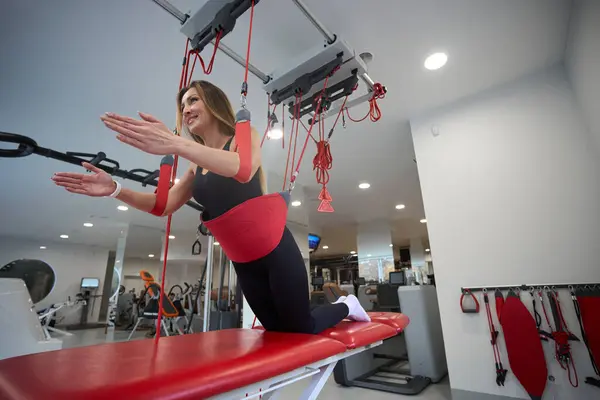 Woman in a health center works out on redcord, using special equipment