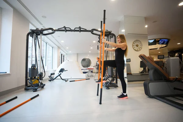 Woman performs physical exercises in a rehabilitation center, special sports sticks are used