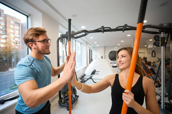 Woman and men greet each other in the gym, they have special sports sticks in their hands
