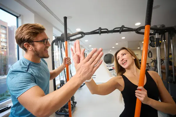 Beautiful woman greets a man in the gym, they have special sports sticks in their hands