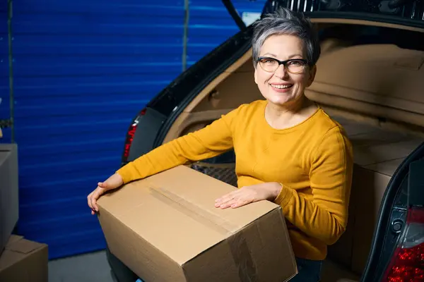 Older Woman Looks Camera Holds Cardboard Box Filled Things — Stock Photo, Image