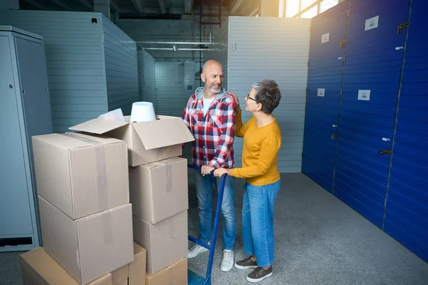 İki kişi büyük mavi bir nakliye arabasıyla bir şeyler taşıyor.