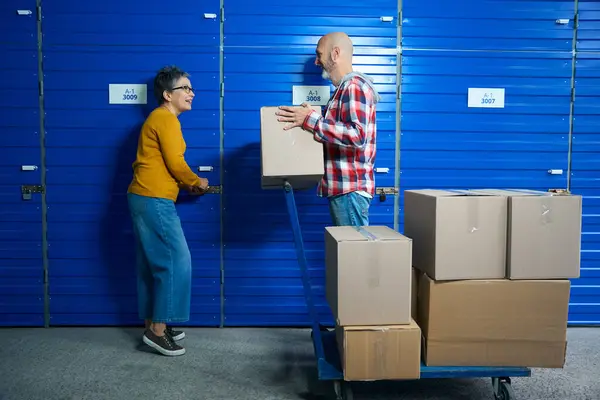 Bir erkek ve bir kadın eşyaları koymak için bir deponun kapısını açıyor.