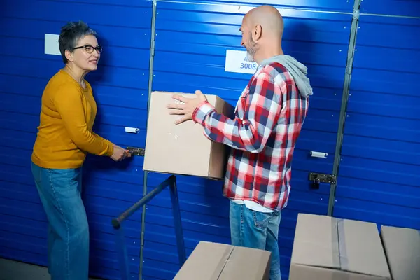 Lady Opens Storage Locker While Man Holds Box — Stock Photo, Image